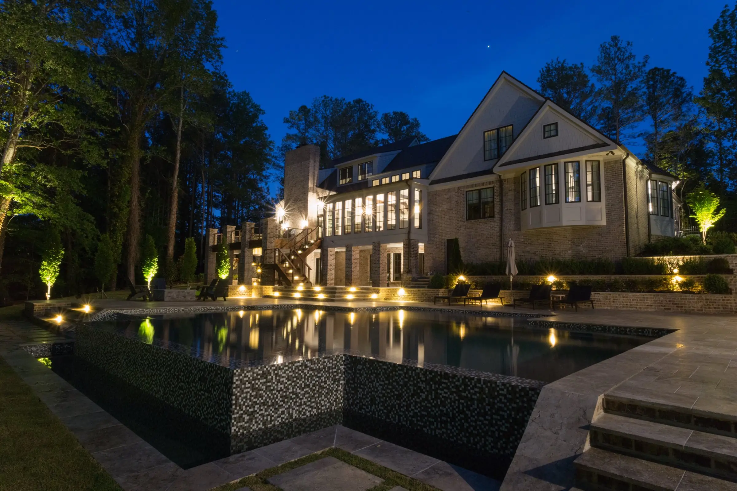 The rebuilt Chadwell pool in Roswell at night, the house lit behind it