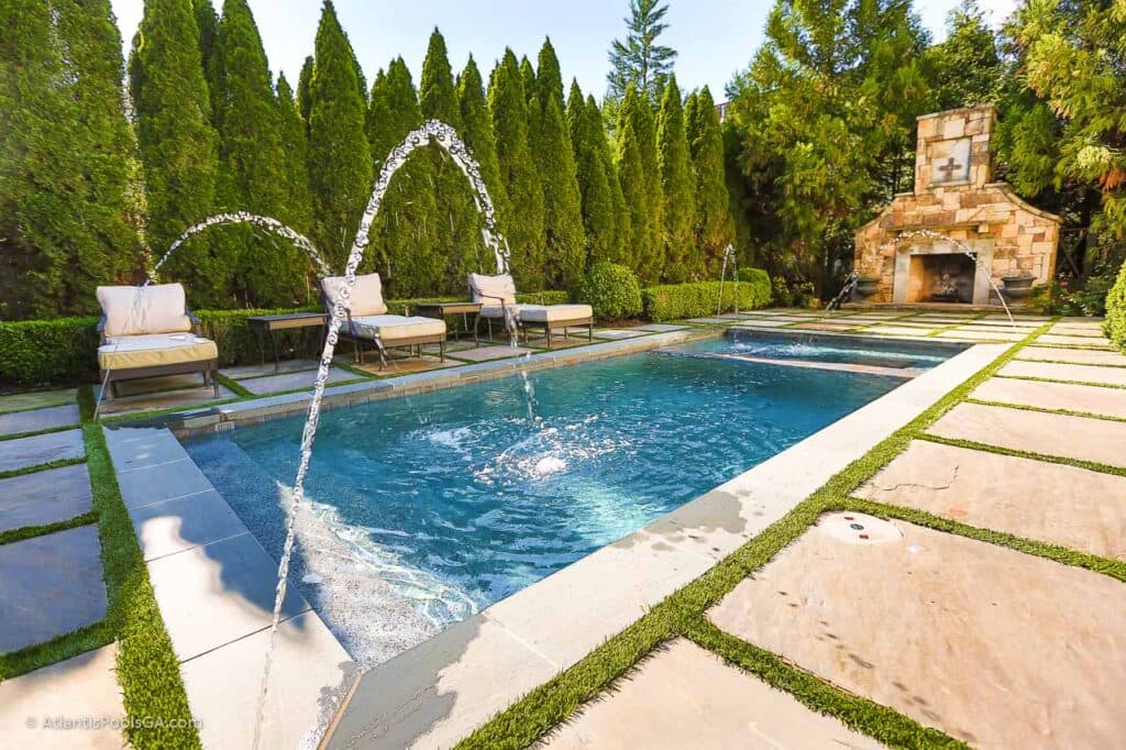 A linear pool deck with in-deck jets and a geometric fireplace feature.