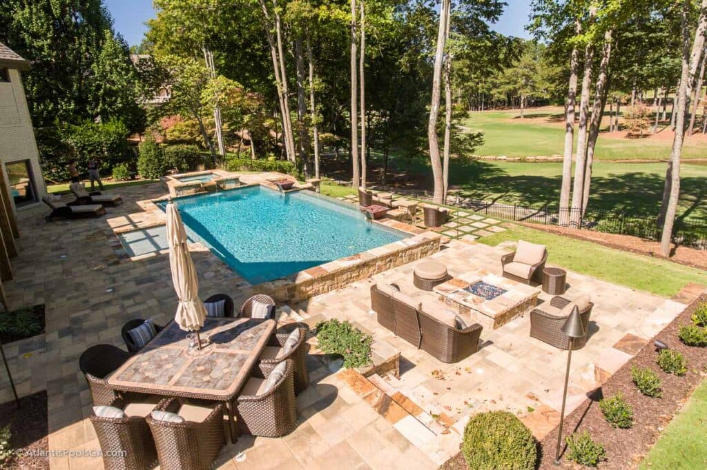 A linear pool and stone entertaining terrace opening toward the golf course beyond