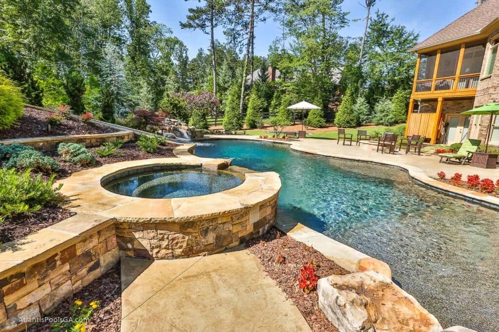 A raised spa integrated with its pool and spilling toward the water below