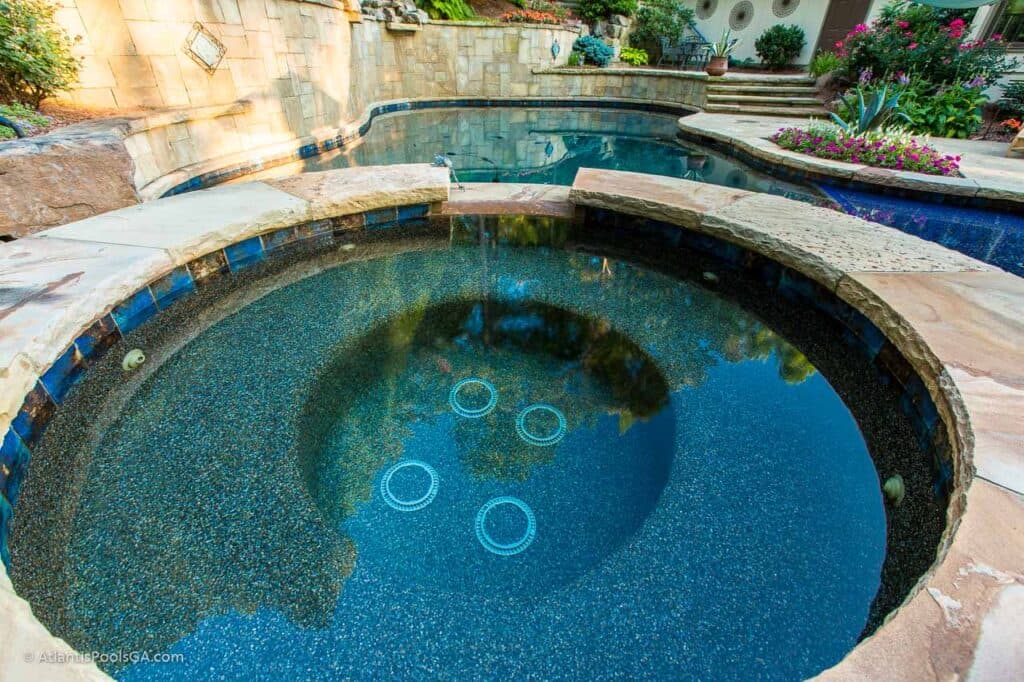 A spa integrated with its pool, sharing sightline and equipment with the main water feature.