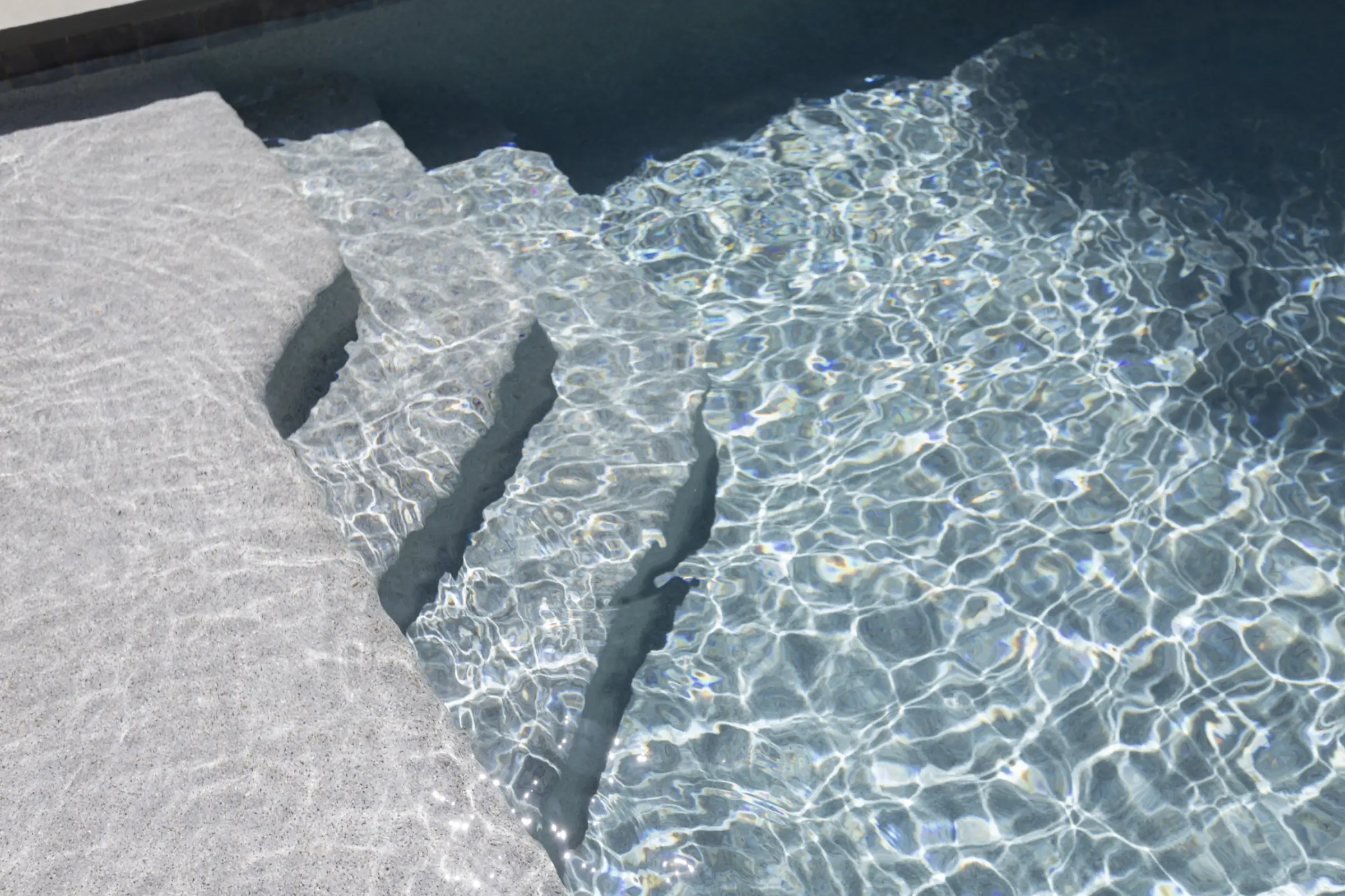 Hand-set stone steps descending into clear pebble-finish water at the Nichol project in Canton